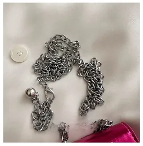 Detailed view of silver chain strap with lobster clasp on fuchsia metallic mini bag