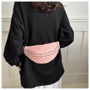 Detail of pink quilted nylon bum bag with double gold zippers on a black sweatshirt