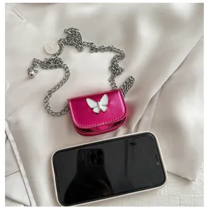 Detailed view of mini fuchsia metallic bag with white butterfly and silver chain strap