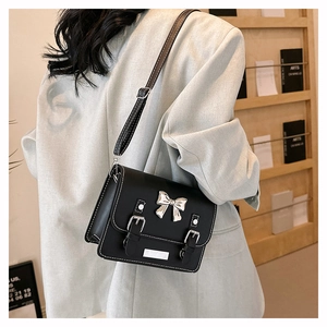 Classic black crossbody bag with silver bow accent and retro buckle straps on back of model