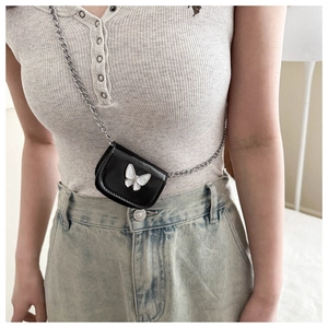 Close-up of mini black leather chain bag featuring a silver butterfly buckle detail