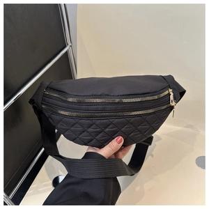 Detail view of black quilted nylon belt bag with gold zippers and adjustable strap