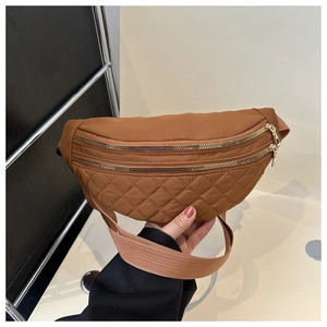 Detail of caramel nylon quilted saddle bag featuring dual gold metal zippers and textured stitching