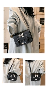 Detail view of black crossbody bag with silver bow buckle and contrast stitching