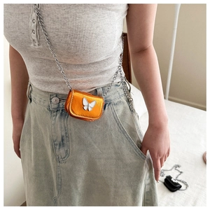 Detailed close-up of a mini orange crossbody bag with a silver butterfly relief on the flap