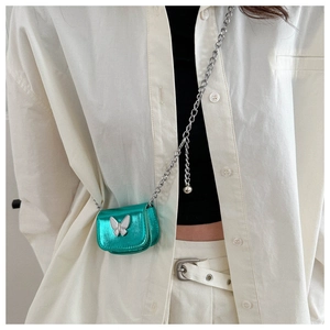 Detailed shot of a mini green metallic crossbody bag with silver chain and butterfly decor