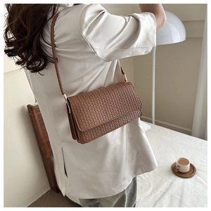 Rear view of a model wearing a brown woven PU leather crossbody bag with flap detail