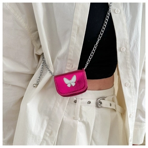 Macro detail of mini fuchsia crossbody bag with silver butterfly emblem and metal chain