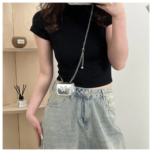 Mini silver crossbody chain bag with butterfly ornament worn over a casual outfit