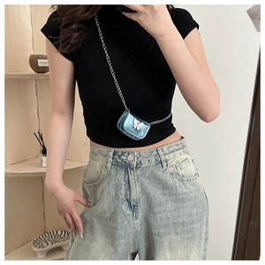 Mini metallic blue crossbody bag with silver butterfly and chain on denim jeans
