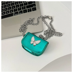 Detailed view of mini metallic green bag with silver chain and white butterfly ornament