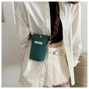 Detail of dark green corduroy crossbody phone bag with FANYIGGA label on model outfit