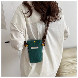 Model wearing dark green corduroy crossbody phone bag with snap closure detail