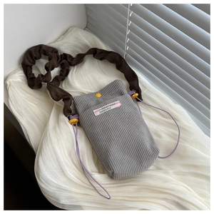 Detail of grey corduroy crossbody phone bag with brown pleated strap and yellow snap