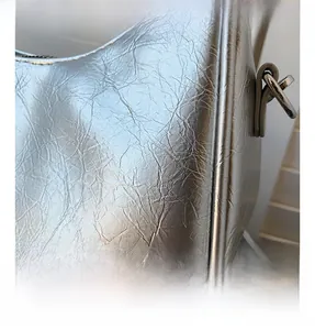 Detail of silver crinkled texture fabric and D-ring buckle on crescent shoulder bag