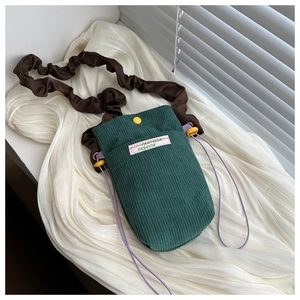 Detail of dark green corduroy phone bag with yellow button and pleated shoulder strap