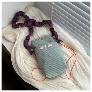 Detail view of mint corduroy bag with purple pleated strap and orange snap button