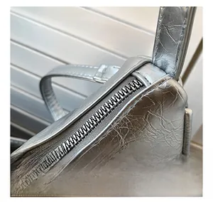 Macro shot of silver metallic crescent bag showing smooth zipper and crinkled texture