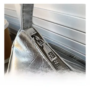 Close-up of smooth metal zipper and silver crinkled texture on a crescent shoulder bag