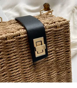 Detailed macro view of retro woven straw bag with black leather strap and gold metal lock