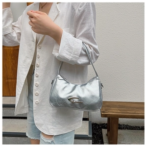 Close-up of silver crescent baguette bag with pleated texture and metallic buckle detail