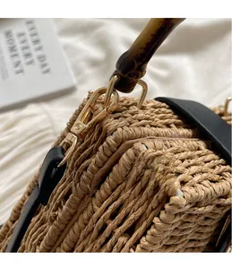 Detail of woven straw handbag featuring bamboo handle and gold hardware hooks