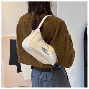 White crescent underarm bag with unique silver metallic buckle on a brown sweater