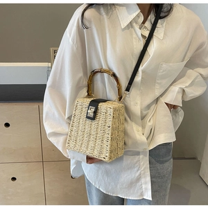 Detail of woven crossbody bag featuring bamboo handle and silver twist-lock closure
