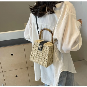 Detailed macro view of handmade woven straw handbag with a bamboo handle and metal lock