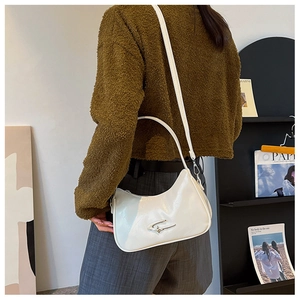 Detail view of a white glossy crescent shoulder bag with silver star buckle on a model