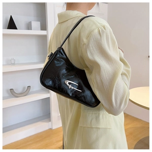 Detail of black glossy crescent shoulder bag with silver star logo and pleated leather
