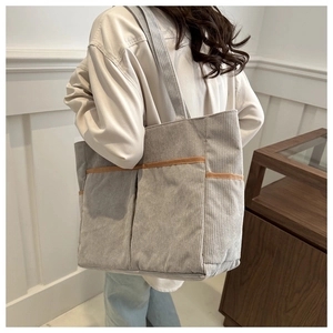 Detail der grauen Cord-Einkaufstasche mit mehreren Taschen und brauner Paspel am Modell