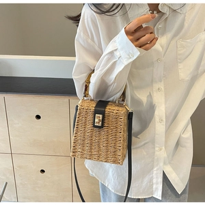 Detail of hand-woven straw bag with bamboo handle and black leather gold lock