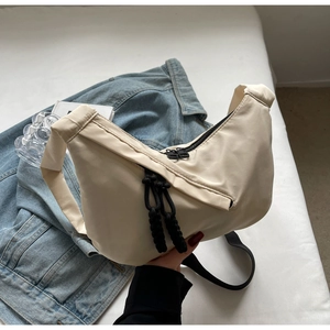 Close-up of off-white crescent tote bag featuring dual zippers with black woven pullers