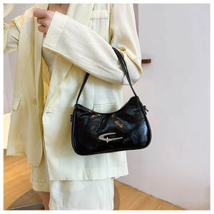 Close-up of black glossy wrinkled leather crescent bag with silver metallic hardware detail
