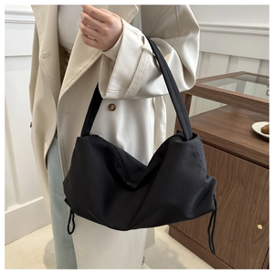Detail of a black nylon hobo bag showing the functional drawstring and smooth texture