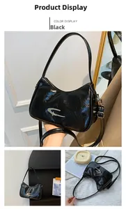Close-up of black wrinkled patent leather crescent bag with silver metallic logo detail