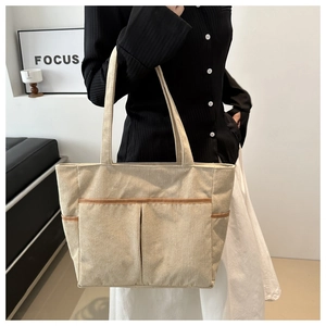 Detailansicht der beigen Cord-Tasche mit großen Taschen und braunen Lederpaspeln