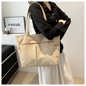 Detail of beige corduroy tote bag with vertical texture and front pockets for daily commute