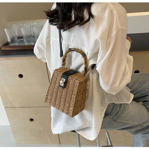 Retro woven straw suitcase bag with bamboo handles and leather strap on a model