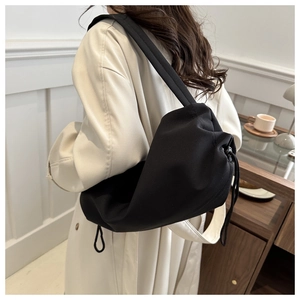 Detail of minimalist black nylon drawstring bag with soft texture and wide shoulder strap