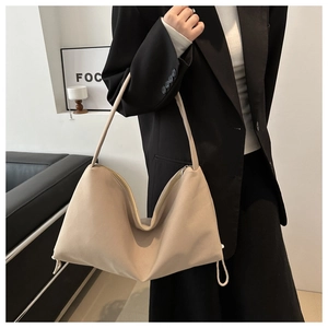 Hobo style nylon shoulder bag in beige shown on model with drawstring side detail