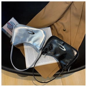 Close-up of metallic silver and glossy black crescent bags with star buckle and wrinkled texture