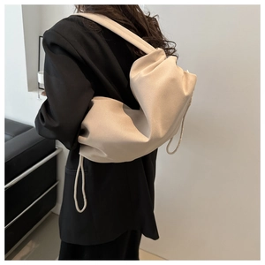 Detail view of the beige nylon drawstring bag with soft pleats on a model's shoulder