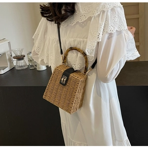 Close-up of woven rattan bag featuring a signature bamboo handle and metallic clasp lock