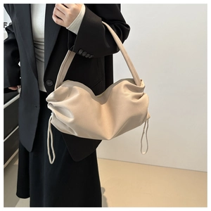 Detailed close-up of beige drawstring hobo bag with soft pleated design and straps