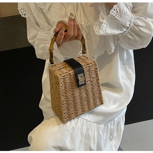Close-up of woven straw handbag featuring vintage bamboo handle and silver twist lock