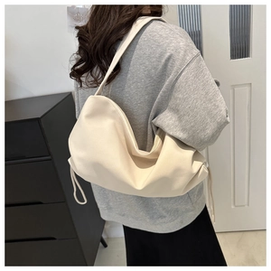 Close-up of a soft cream nylon hobo bag with drawstring pleats worn by a model