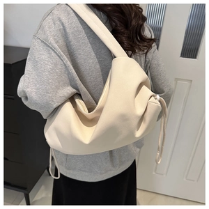 Minimalist beige nylon drawstring shoulder bag with soft cloud silhouette worn by model