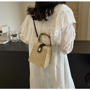 Close-up of woven straw handbag featuring vintage bamboo handle and gold twist lock detail